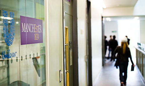 A woman walking by signs for the University and Unilever