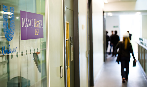 A woman walking past signs for the University and Unilever