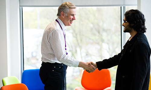 Two men smiling and shaking hands