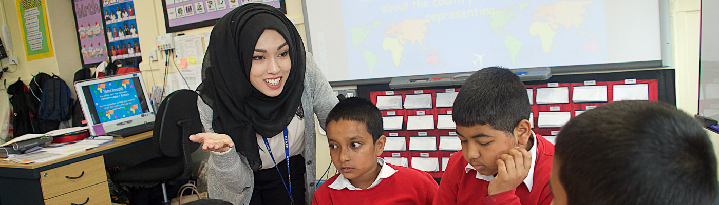 A teacher engages with her students around a table in a classroom