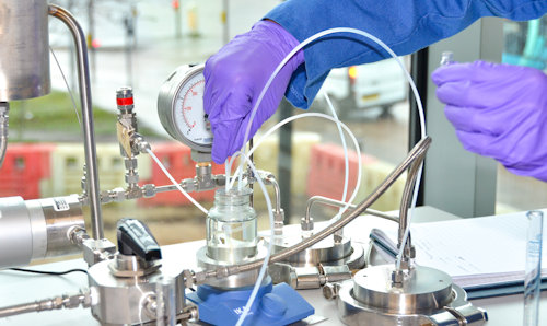 Close up of hands in safety gloves putting a tube into a chemical solution