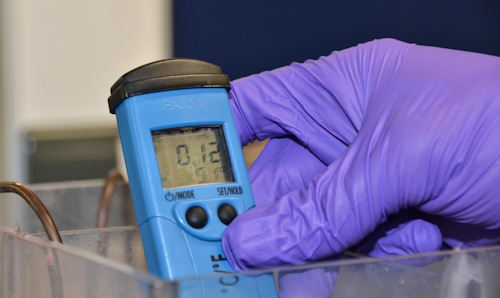 Close up of hands in safety gloves taking a reading from an LCD display