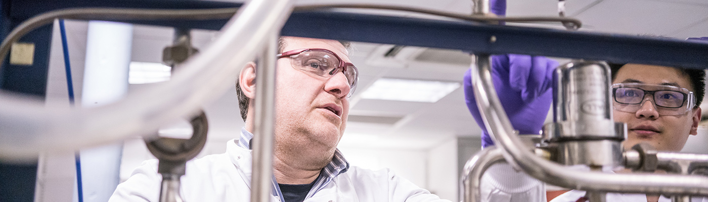 A researcher and his student operating biochemical engineering equipment