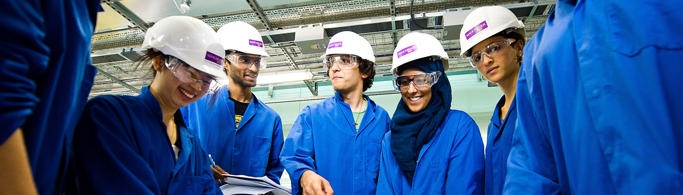 A huddle of students in lab coats and hard hats