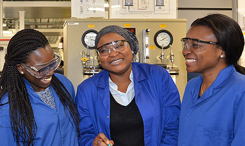Three female students in lab coats laughing together
