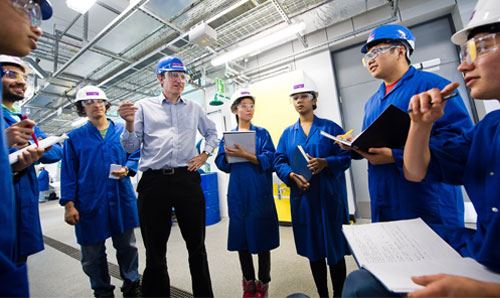 Group of chemical engineering students in lab wearing blue lab coats