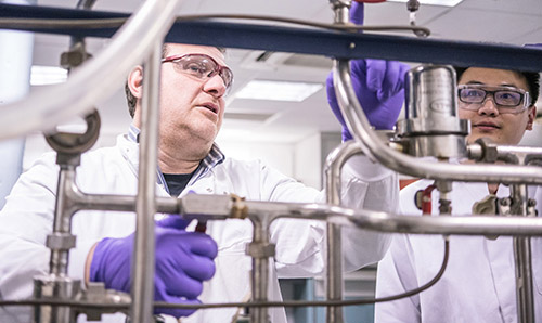 A researcher and his student operating biochemical engineering equipment