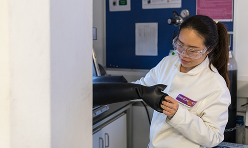 Female researcher pulling on specialised rubber gloves