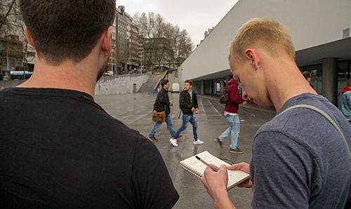 Two students taking notes as they walk around a foreign city