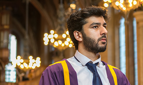 Male student in graduation robe primed to pick up his degree